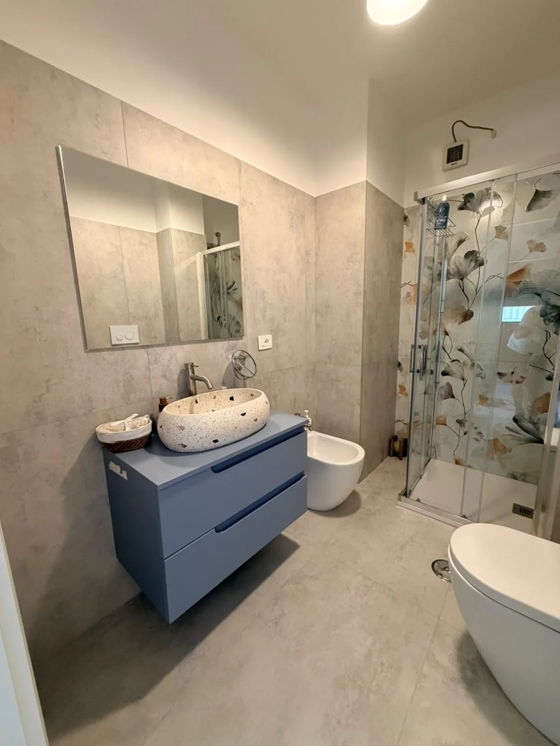 Rivestimenti decorativi e un mobile blu definiscono l’ambiente.
